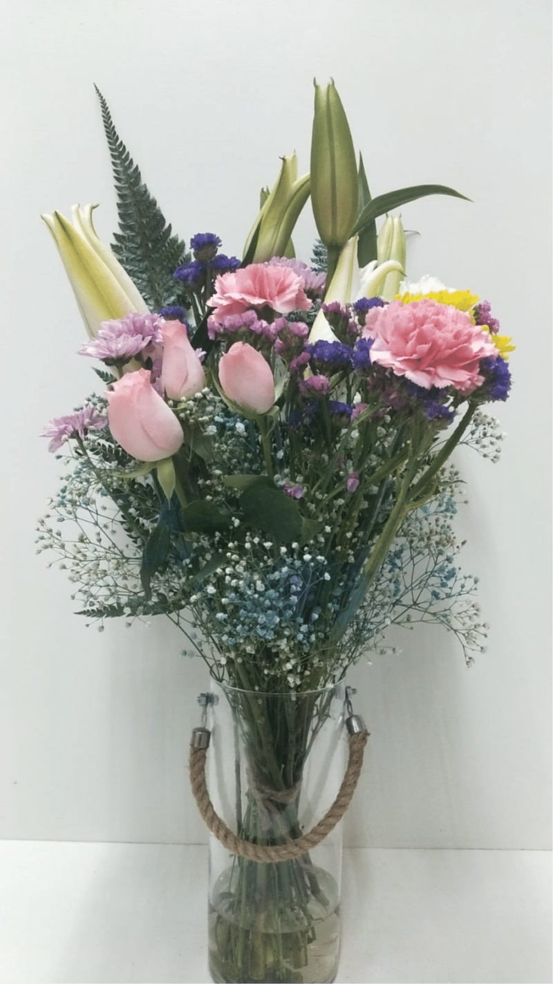 Flower arrangement with Fragrant Oriental Lily, Spray Daisy , Blue Daisy Statice, Carnations and Roses in Cylindrical Vase